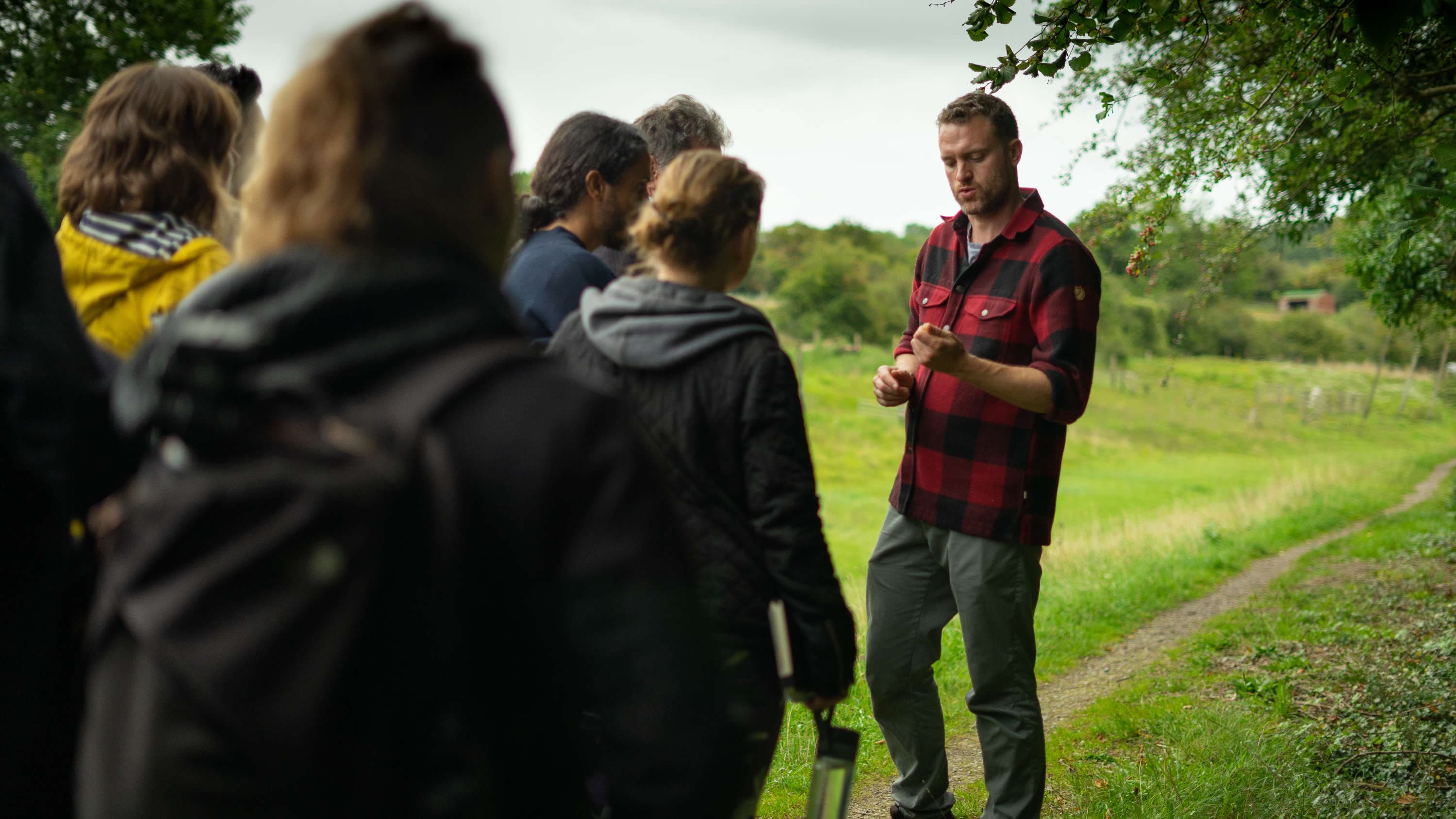 A guide talking to a small group of walkers on a green hillside